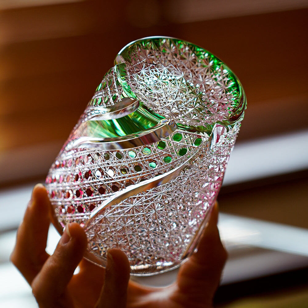 Angled Edo Kiriko Kingyo Nishiki whisky glass with pink fish engraving and green accents