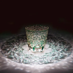 Edo Kiriko Emerald Starburst whisky glass on dark surface with green light reflection