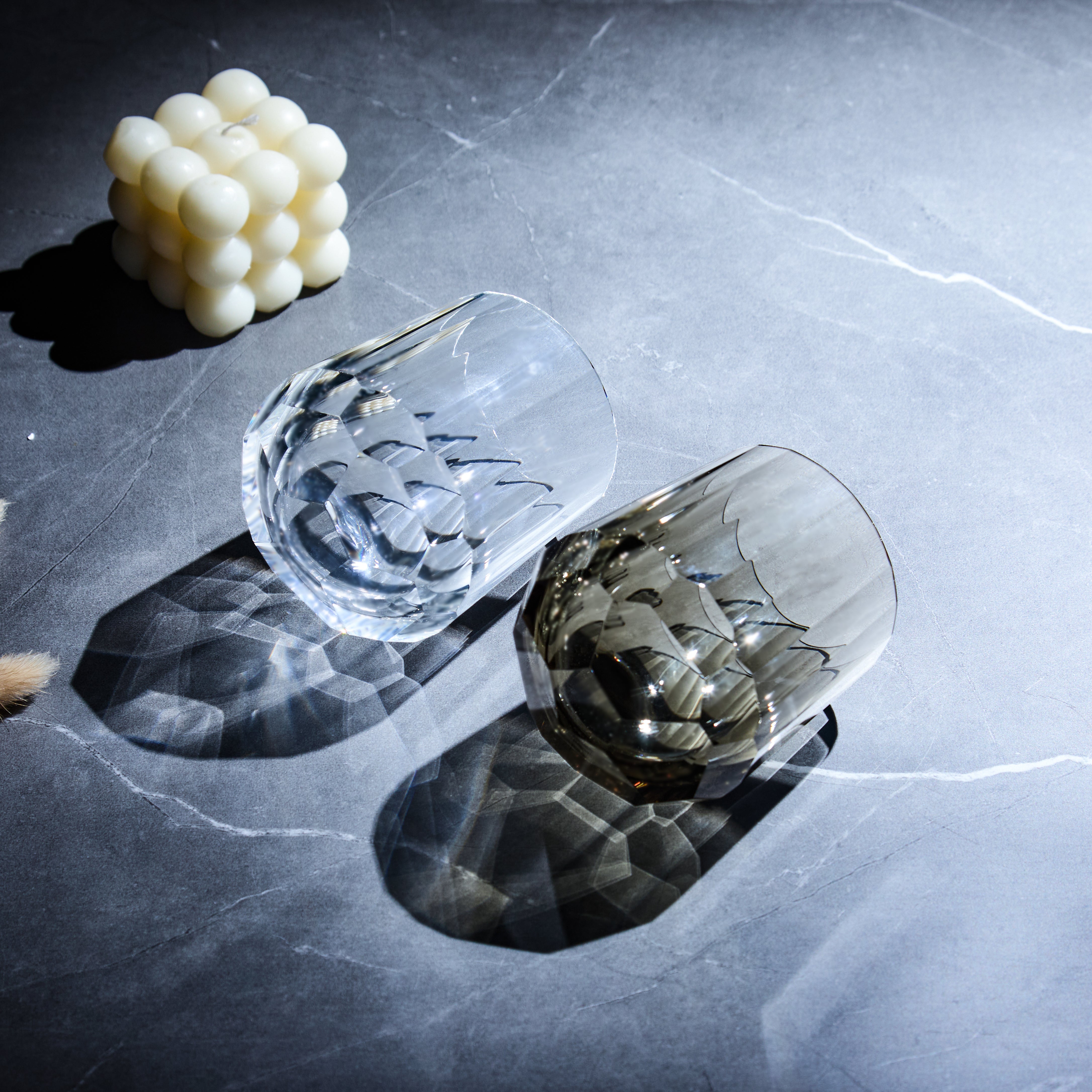 Overhead view of clear and smoky Edo Kiriko Kage-Tate whisky glasses lying on stone