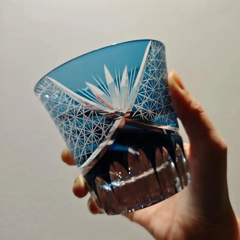 Edo Kiriko Red Chrysanthemum whisky glass held in hand with blue floral motif