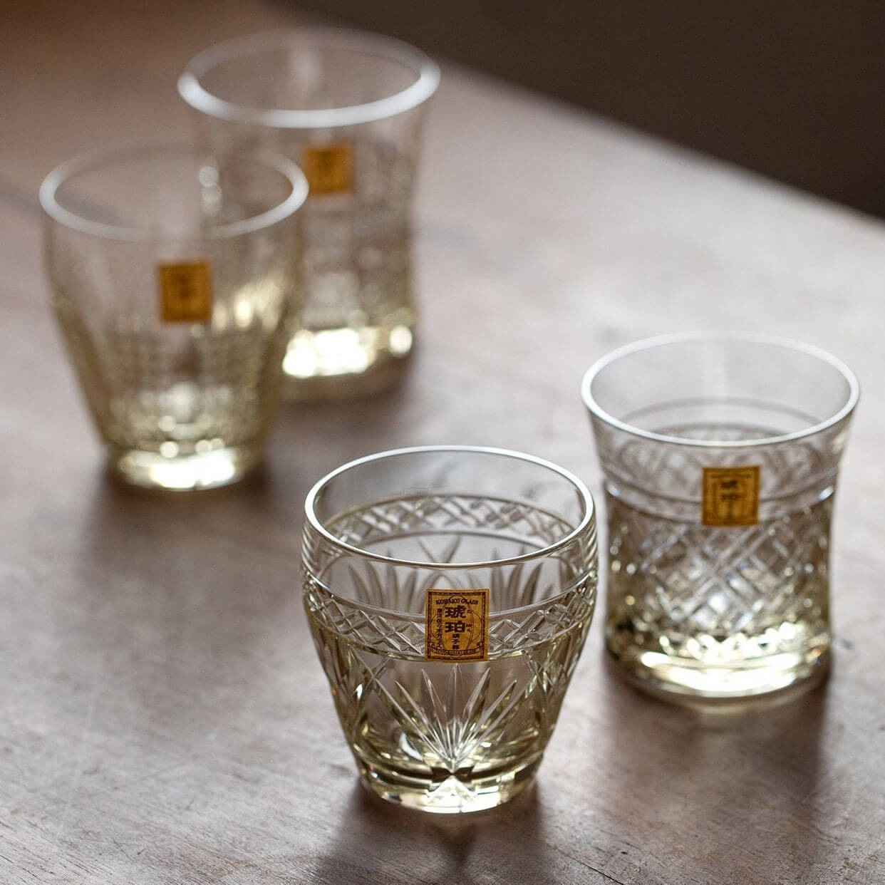 Three Kohaku Kiriko glasses arranged on a wood table, with the rounded glass in front
