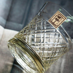 Kohaku Kagome glass lying on its side, showing crossed lattice cuts and paper label