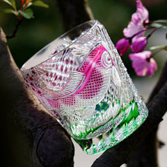 Edo Kiriko Kingyo Nishiki whisky glass outdoors with pink flowers and green crystal base