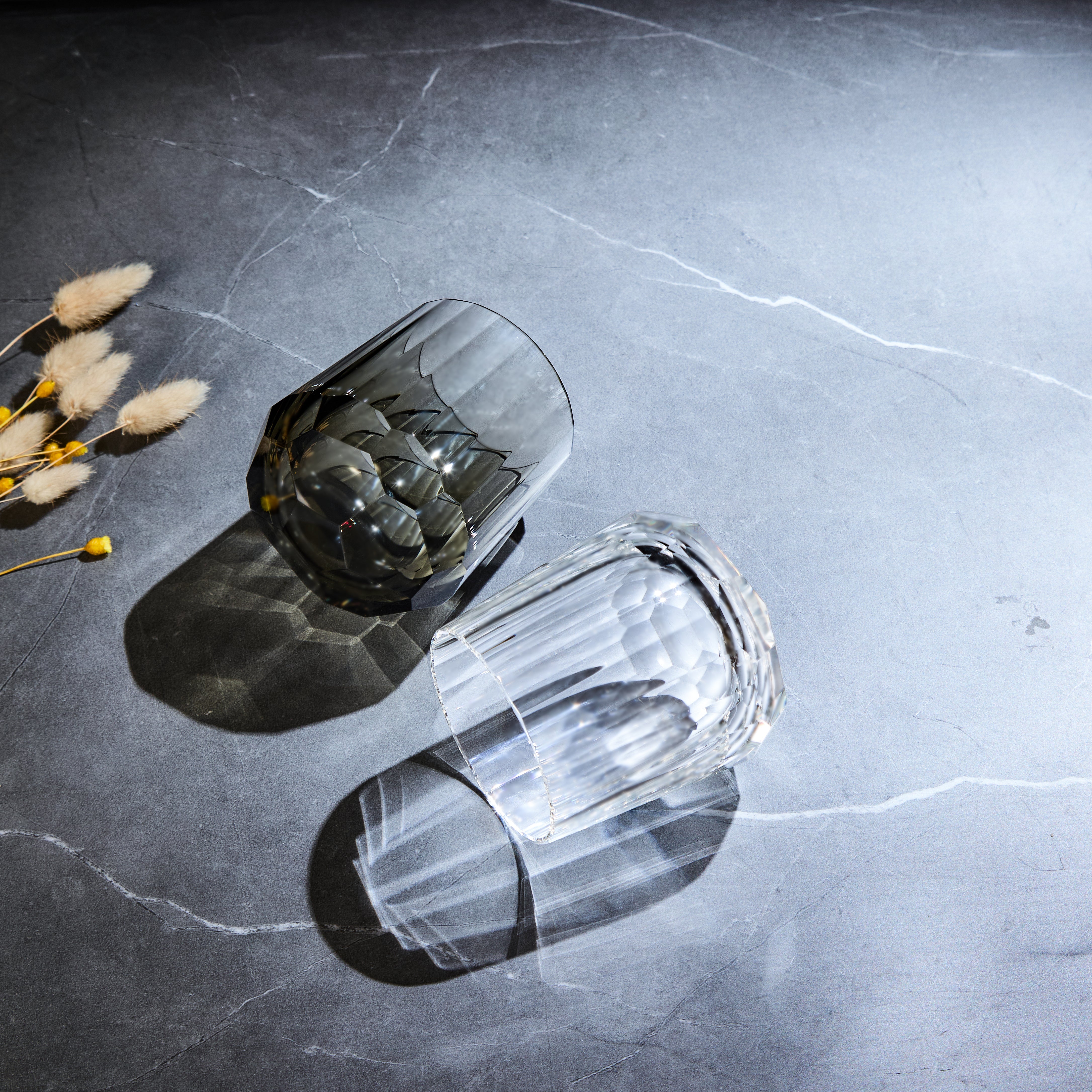 Edo Kiriko Kage-Tate whisky glasses angled on stone with clear and smoky faceted bodies