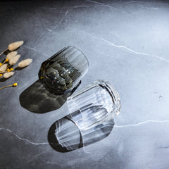 Edo Kiriko Kage-Tate whisky glasses angled on stone with clear and smoky faceted bodies