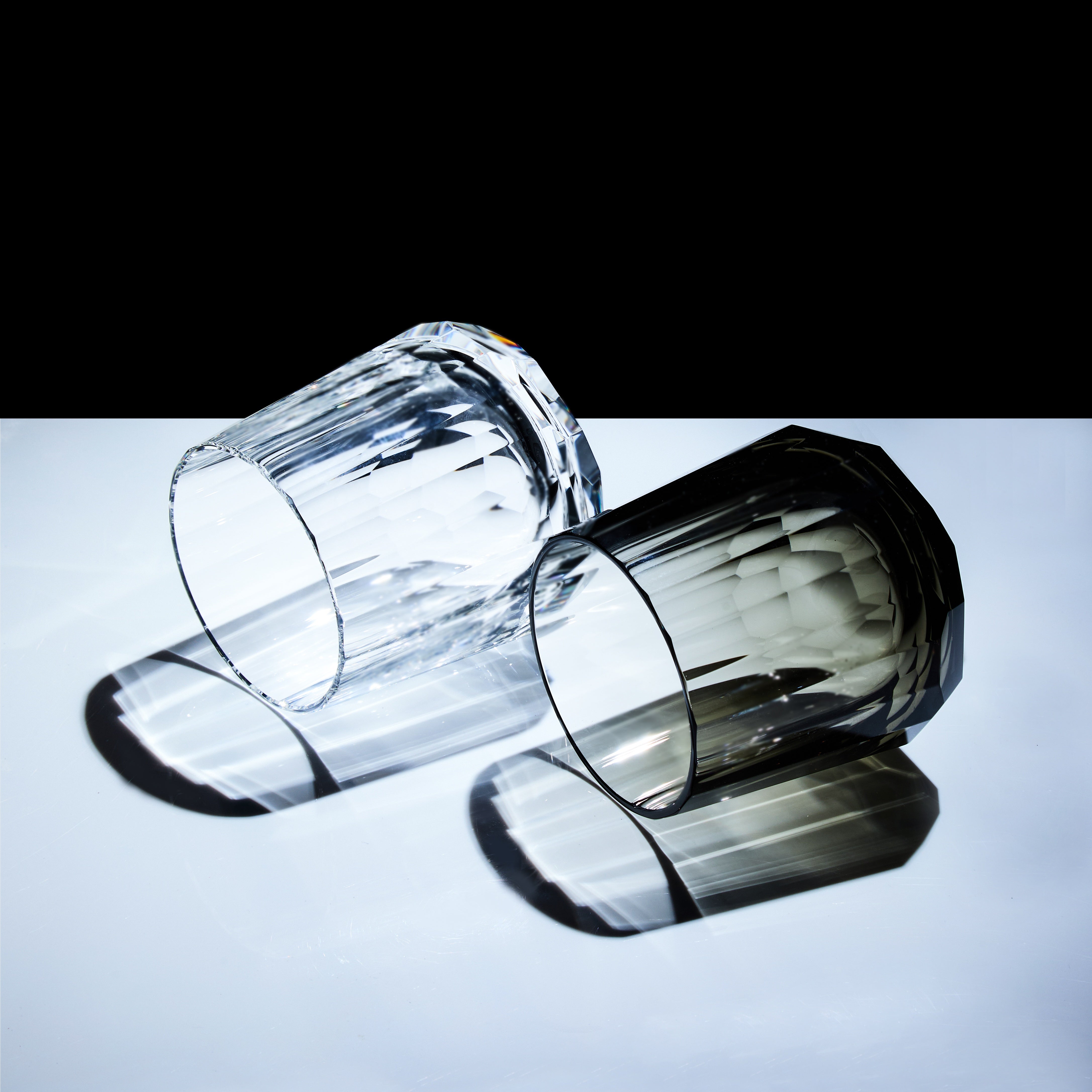 Clear and smoky Edo Kiriko Kage-Tate whisky glasses lying down with prism-like shadows