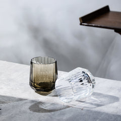 Clear and smoky Edo Kiriko Kage-Tate whisky glasses on stone surface with soft reflections