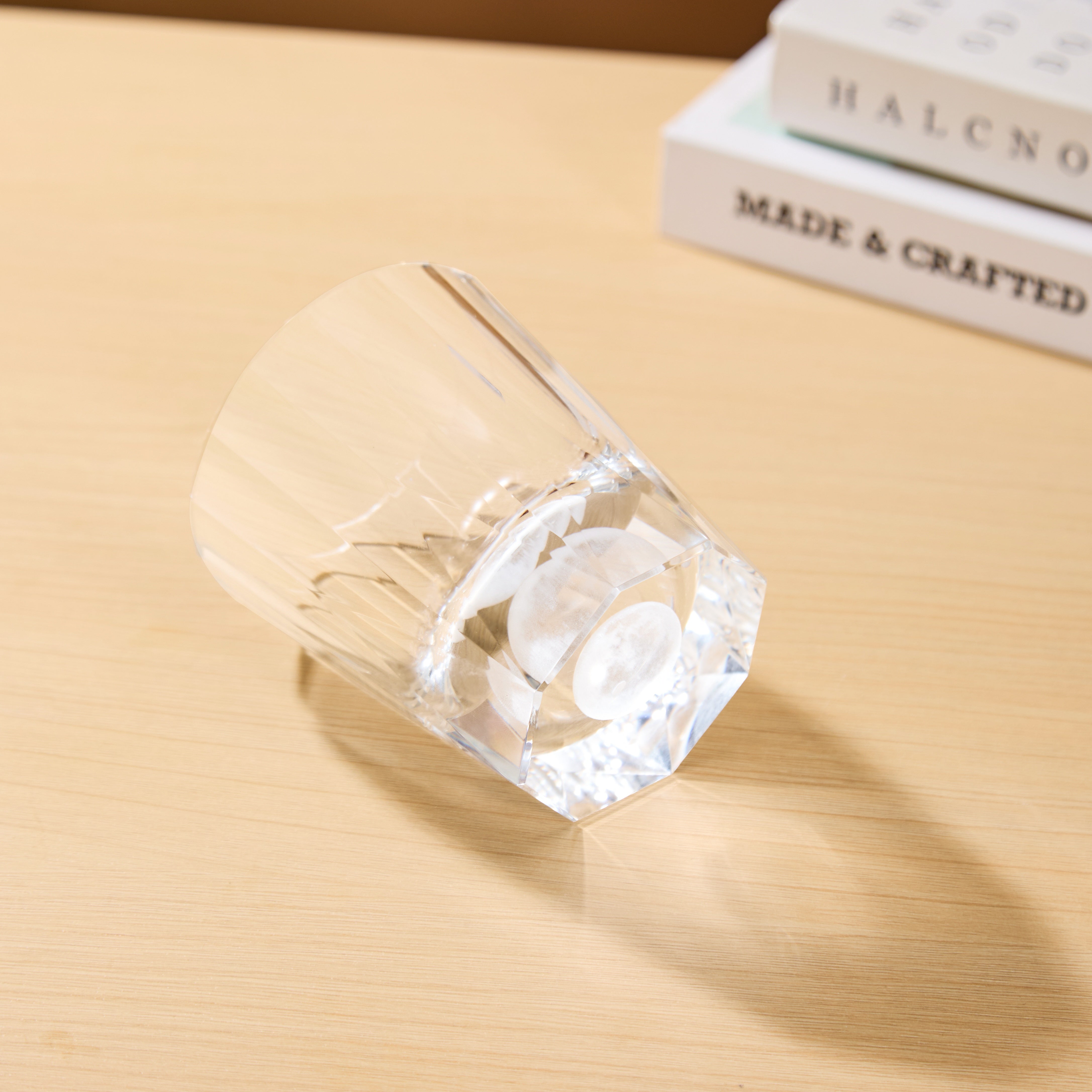 Edo Kiriko Tsukikage whisky glass lying on light wood surface showing crystal base