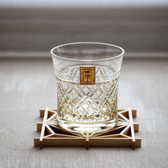 Empty Kohaku Kagome glass with crossed lattice cutting on a geometric wooden coaster