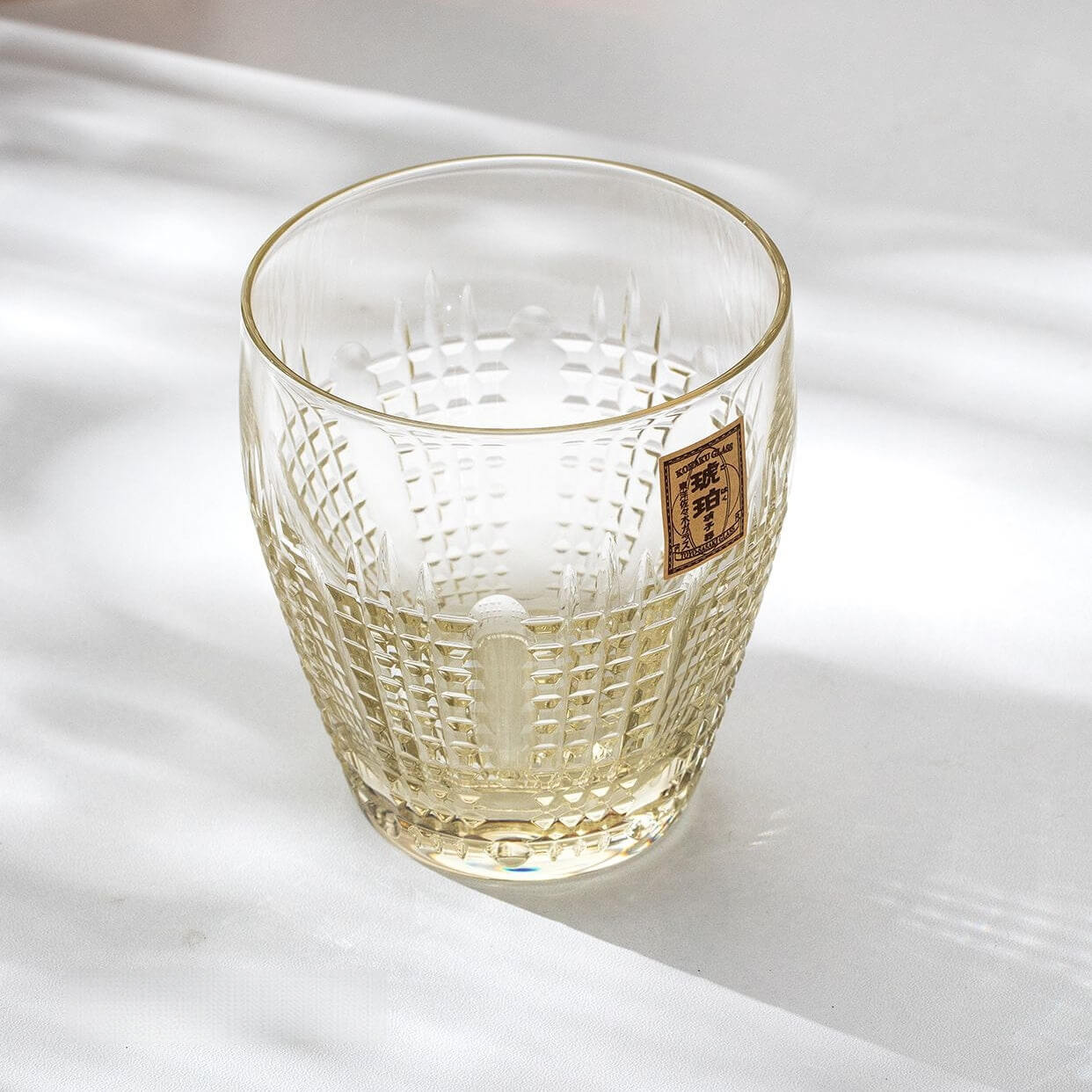 Empty Kohaku Nanako glass on a light table, with fine dotted cuts and a gold label