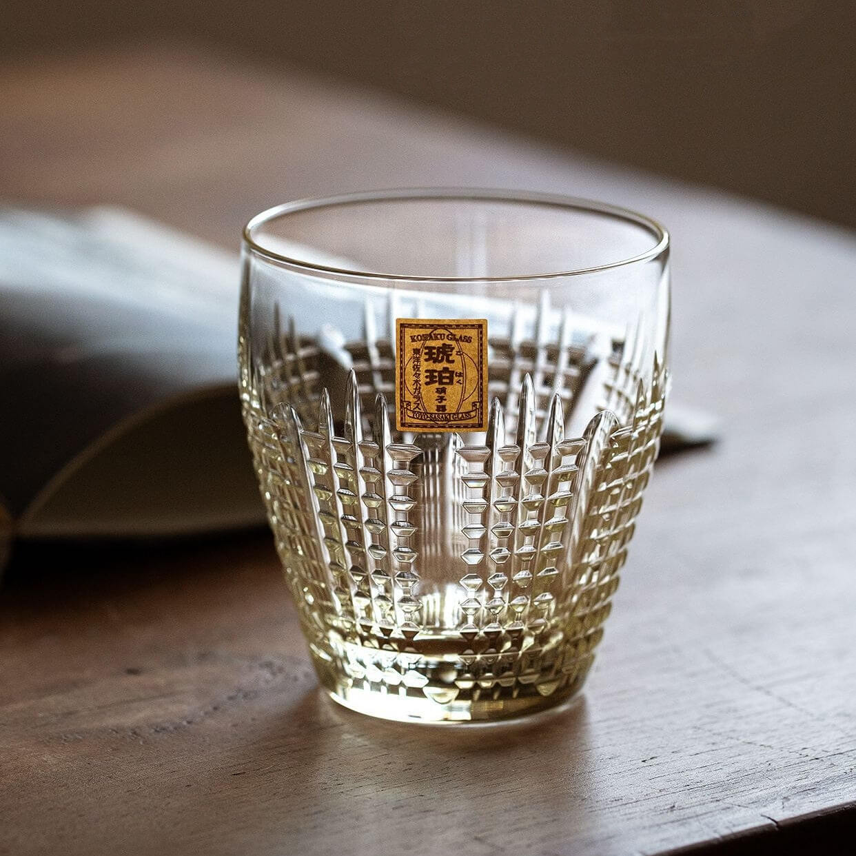 Empty Kohaku Nanako glass on a wood table, showing dense vertical and dotted cuts