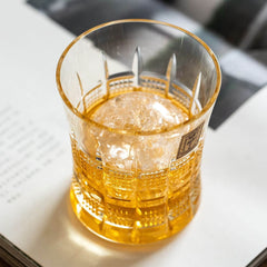Top view of an amber drink with ice in a Kohaku Yarai glass on an open book